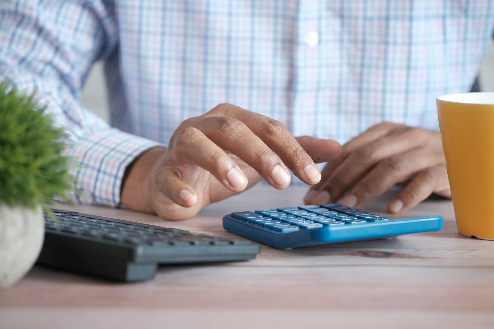 Hands on a desk calculator beside a keyboard