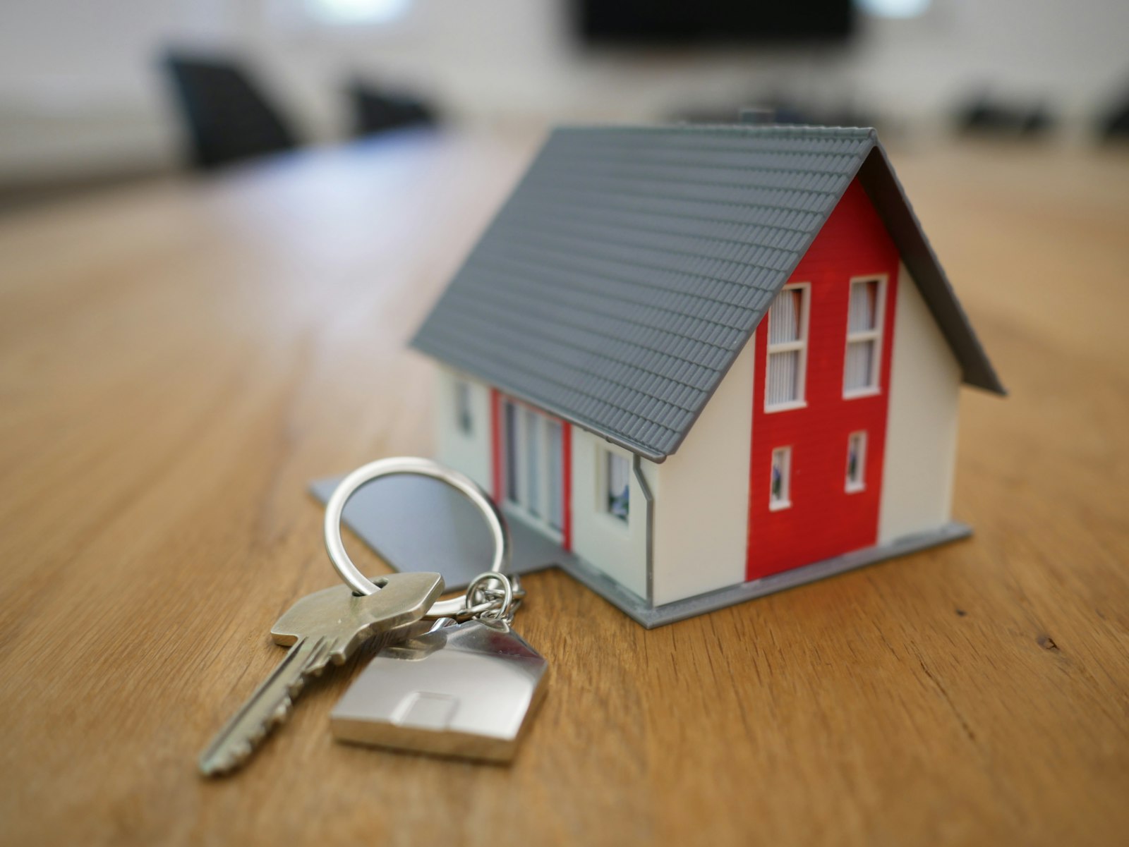 A small model house with a house key on a table